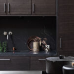 Beiset kjøkken i tre med benkeplate av rustfritt stål og med svart marmor